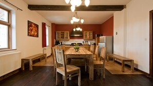 Une cuisine avec des meubles de rangement en bois, une table à manger avec des chaises et un luminaire suspendu.