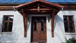 Un bâtiment doté d’une porte d’entrée en bois, d’un toit à deux versants et de deux fenêtres de part et d’autre de la porte.
