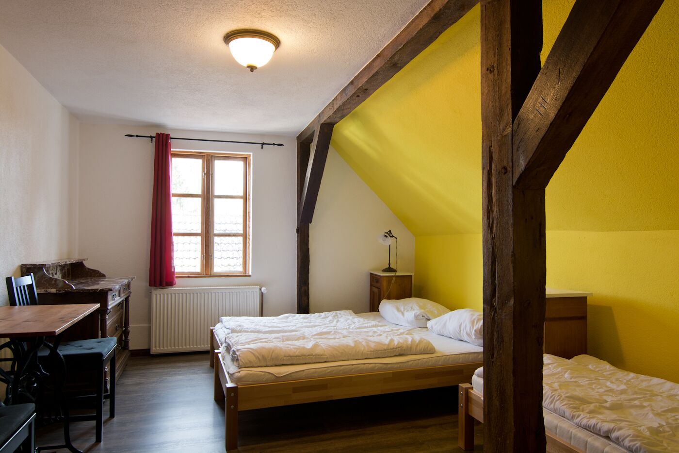 A bedroom with two beds, a desk, and a chair.