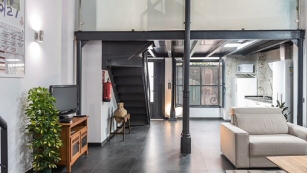Ein modernes Interieur mit einer Treppe, die zu einer zweiten Etage führt, einer Couch, einem Fernseher und einer Topfpflanze.