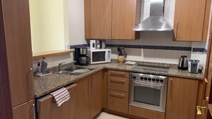 Eine Küche mit Holzausstattung, einer Edelstahl-Dunstabzugshaube, einer Mikrowelle, einer Kaffeemaschine, einem Toaster und einem Spülbecken.