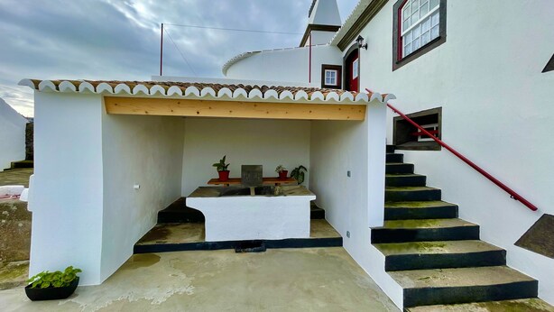 A white building with a small covered outdoor area, a staircase with a red handrail, and a red door. - Casa do Avô José Alves (T3), Country House - Rural Tourism  (Cabo da Praia)