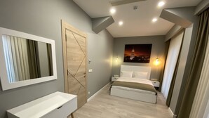 A modern bedroom with a large bed, bedside tables, a built-in bench, a large mirror, and a painting on the wall. - Li Hotel Pera (Istanbul)
