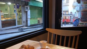 A table with croissants, a cup of coffee, and a view of a street outside. - Li Hotel Pera (Istanbul)