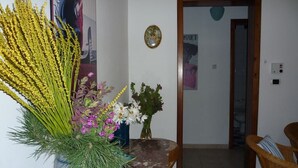 Ein Essbereich mit einem Marmortisch, einer Blumenvase und einem Korbstuhl.