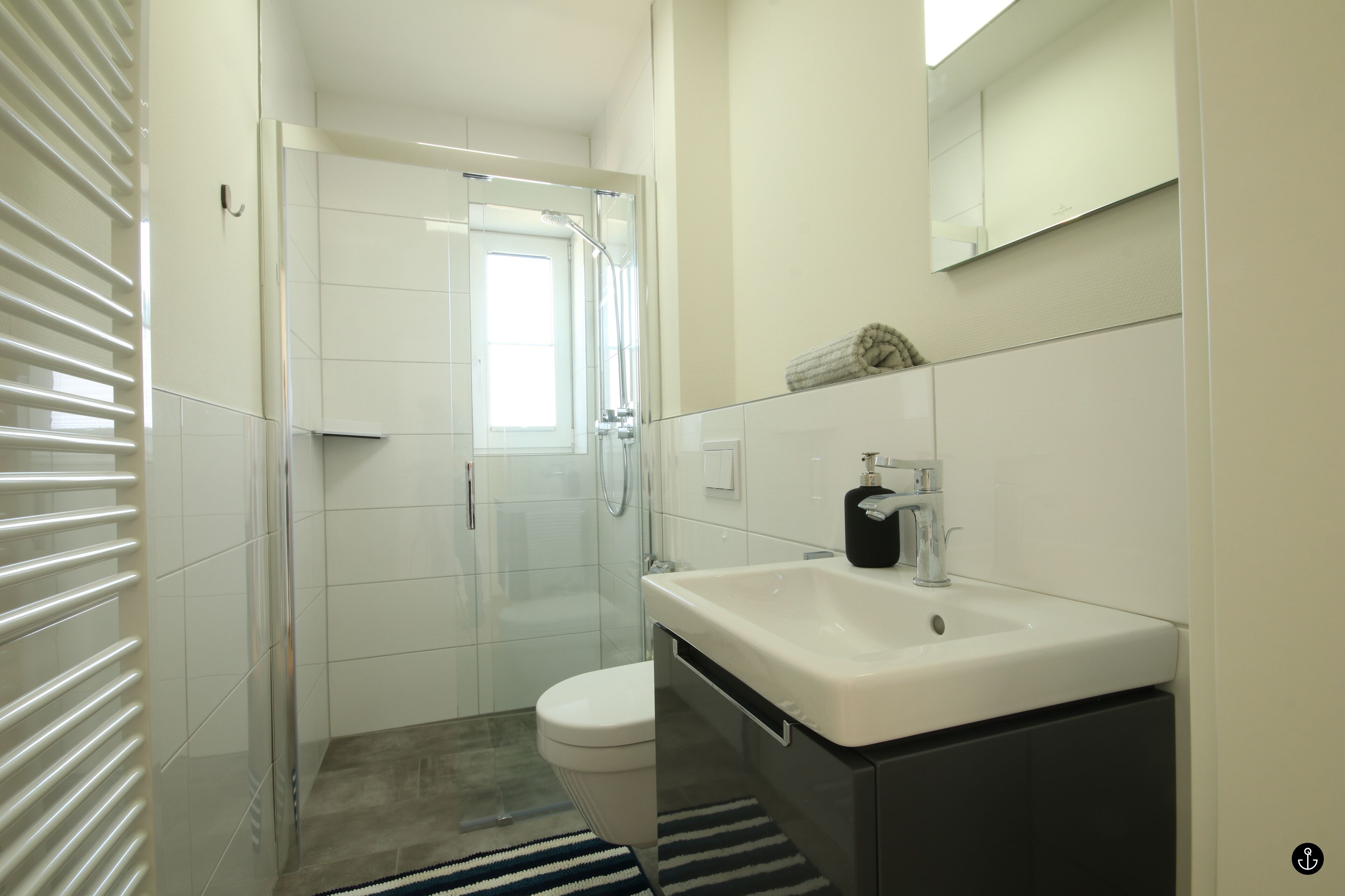 A modern bathroom with a glass shower enclosure, a white sink, and a toilet.