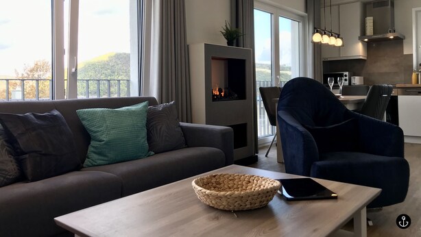 A modern living room with a sofa, a coffee table, and a view of the outdoors. - Sonnenweg 1 (Diemelsee)