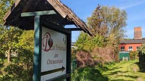 En rustik träskylt med en pil som visar riktningen till en plats som heter ”Das Ferienhaus am Ostseestrand”.