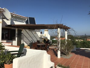 A patio area with a table and chairs, a pergola, and a satellite dish.