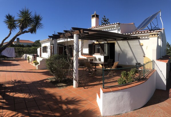A villa with a patio, outdoor furniture, and a pergola.