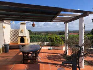 An outdoor patio with a table and chairs, a pergola, and a view of the landscape.