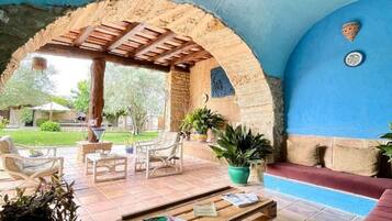 Un área de patio al aire libre con una pérgola de madera, asientos y plantas en macetas.
