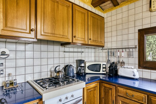 A kitchen with wooden cabinets, a gas stove, a microwave, and a toaster.