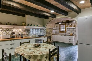 A kitchen with a dining table, chairs, and a refrigerator.