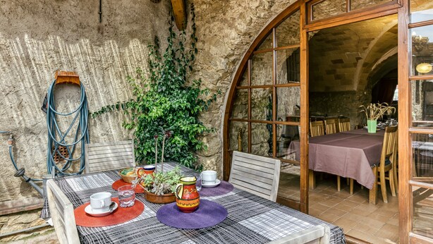 Un comedor rústico con una mesa para dos, techo de paja y pared de piedra.