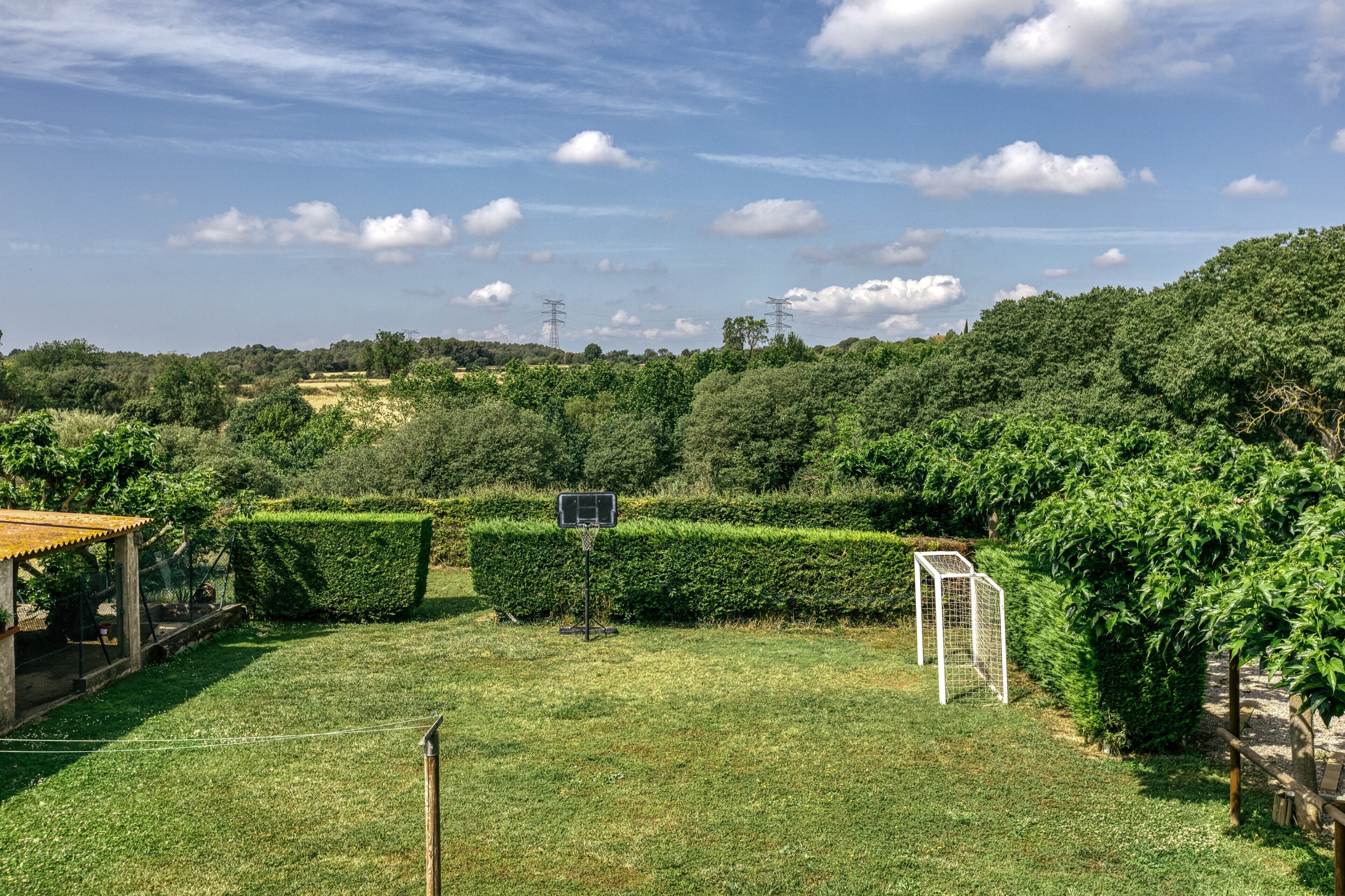A well-maintained garden with a basketball hoop, neatly trimmed hedges, and a gazebo.