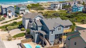Zona residencial con varias casas, una piscina y una playa al fondo.