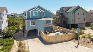 A two-story house with a wooden deck, a small porch, and a backyard with a grill.