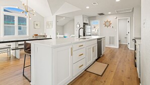 Una cocina moderna con armarios blancos, una isla central y una zona de comedor con banco.
