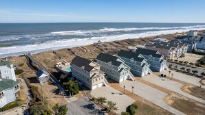 A coastal residential area with houses, a beach, and a boardwalk. - Sandbox 8 Bedroom Home in Kitty Hawk Shores (Kill Devil Hills)