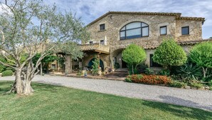 A stone building with a covered patio, a gravel driveway, and various plants and trees. - Country House 'Cal Secretari' with Shared Pool, Private Terrace and Wi-Fi (SAUS CAMALLERA LLAMPAIES)
