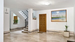 Ein geräumiger Flur mit Holztür, Treppe, Fliesenboden und einem gerahmten Kunstwerk an der Wand.