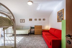 A room with bunk beds, a red sofa, a wooden cabinet, and framed pictures on the wall. - Apartment "Bilocale Rosa" with Sea View, Private Terrace, and Air Conditioning (Santa Cesarea Terme)