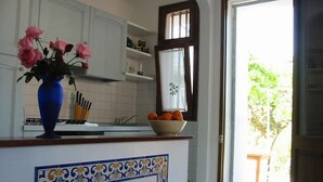 Una cocina con un jarrón azul de flores, un cuenco de naranjas y un salpicadero de azulejos.