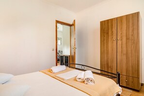 A bedroom with a bed, a wooden wardrobe, and a mirror.