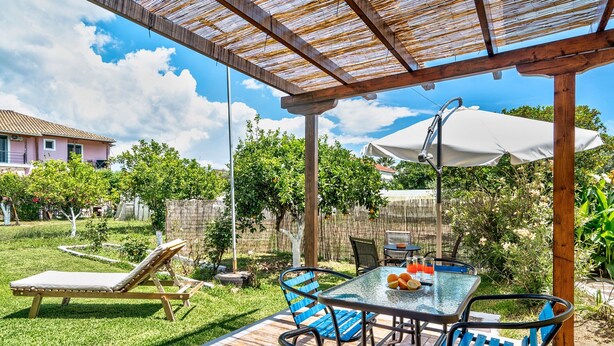 A patio with a table and chairs, a lounge chair, and a pergola. - Holiday Home 'Garden House Lefkada' with Shared Terrace, Wi-Fi and Air Conditioning (Lefkada)