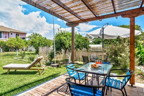 A patio with a table and chairs, a lounge chair, and a pergola.