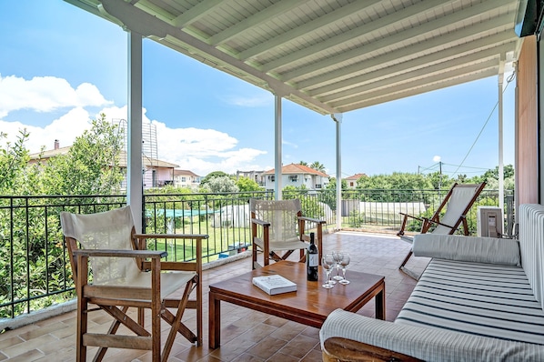 A covered outdoor seating area with a table, chairs, and a sofa.