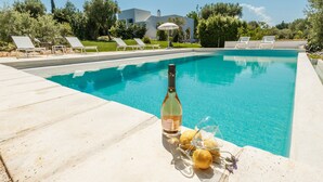 A swimming pool with lounge chairs, a bottle of wine, and lemons on the edge. - "Villa Filara" with Private Pool, Private Terraces & Wi-Fi (carovigno)