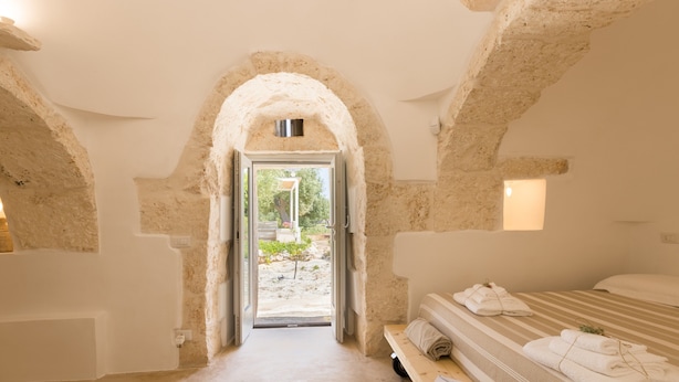 A room with a stone archway, a bed with towels, and a view of greenery outside. - "Villa Filara" with Private Pool, Private Terraces & Wi-Fi (carovigno)