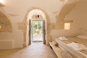 Habitació amb un arc de pedra, un llit amb tovalloles i vista a la verdura a l'exterior.