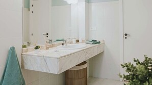 Un baño con un espejo grande, dos lavamanos y un inodoro.