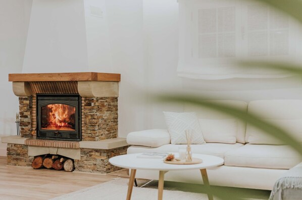 A living room with a stone fireplace, a white sofa, and a round coffee table.