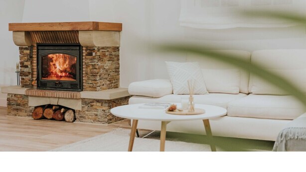 Una sala de estar con chimenea de piedra, un sofá blanco y una mesa de centro redonda.