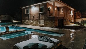 Una casa de dos pisos con piscina, un porche cubierto y una escalera que conduce a un balcón.