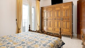 A bedroom with a bed, wooden wardrobe, and a television on the wall.