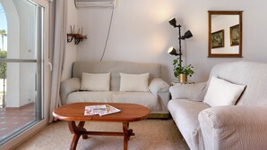 A living room with a sofa, a coffee table, an air conditioner, a lamp, and a framed picture on the wall.