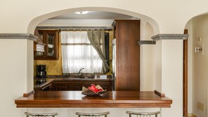 Cucina con isola in legno, sgabelli da bar e una finestra con tende.