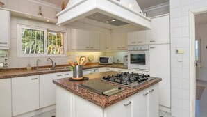 Eine moderne Küche mit weißen Schränken, einer Arbeitsplatte aus Granit, einem Gasherd und einer Mikrowelle.