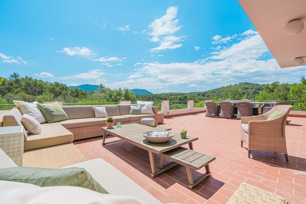 Une terrasse extérieure aménagée avec un canapé, des chaises, une table et un espace barbecue.