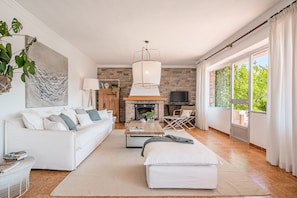 Un salon moderne avec un canapé blanc, une table basse, une cheminée et une grande fenêtre avec des rideaux.