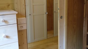 A wooden interior with a wardrobe, a dresser, and a door leading to another room.