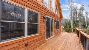 A wooden deck with large windows and a view of a forest.