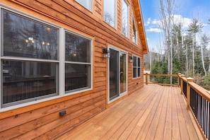 A wooden deck with large windows and a view of a forest. - Paradise Valley Lodge (Bethel)