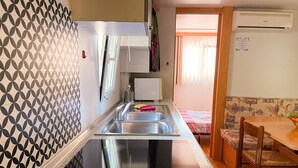 Eine kleine Küche mit Spüle, Kühlschrank und einem Essbereich mit Tisch und Stühlen.