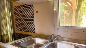 Eine Küche mit zwei Edelstahl-Spülen, einem Fenster und einer Wand mit Muster.